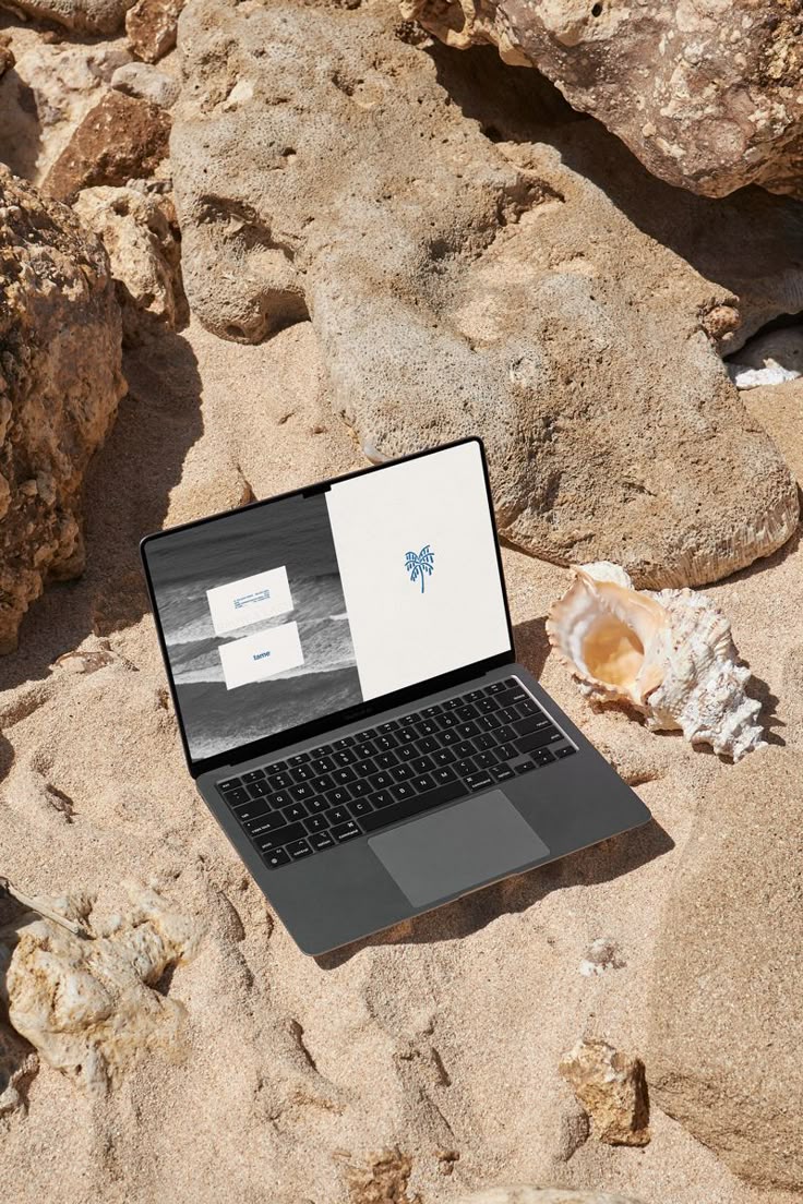 Brand design displayed on a MacBook among rocks and shells